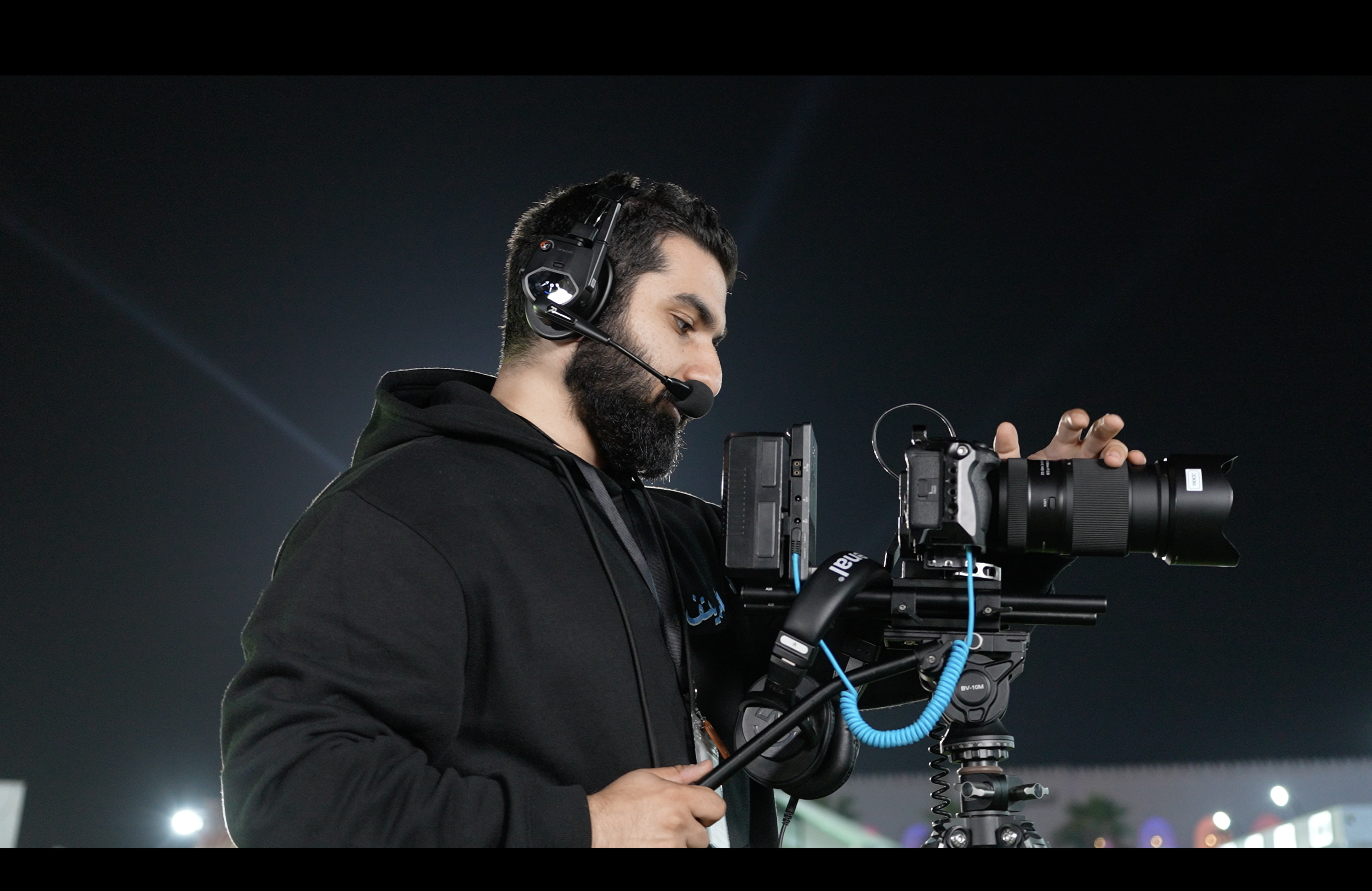 Moris Dakar wearing a headset and operating a professional video camera.