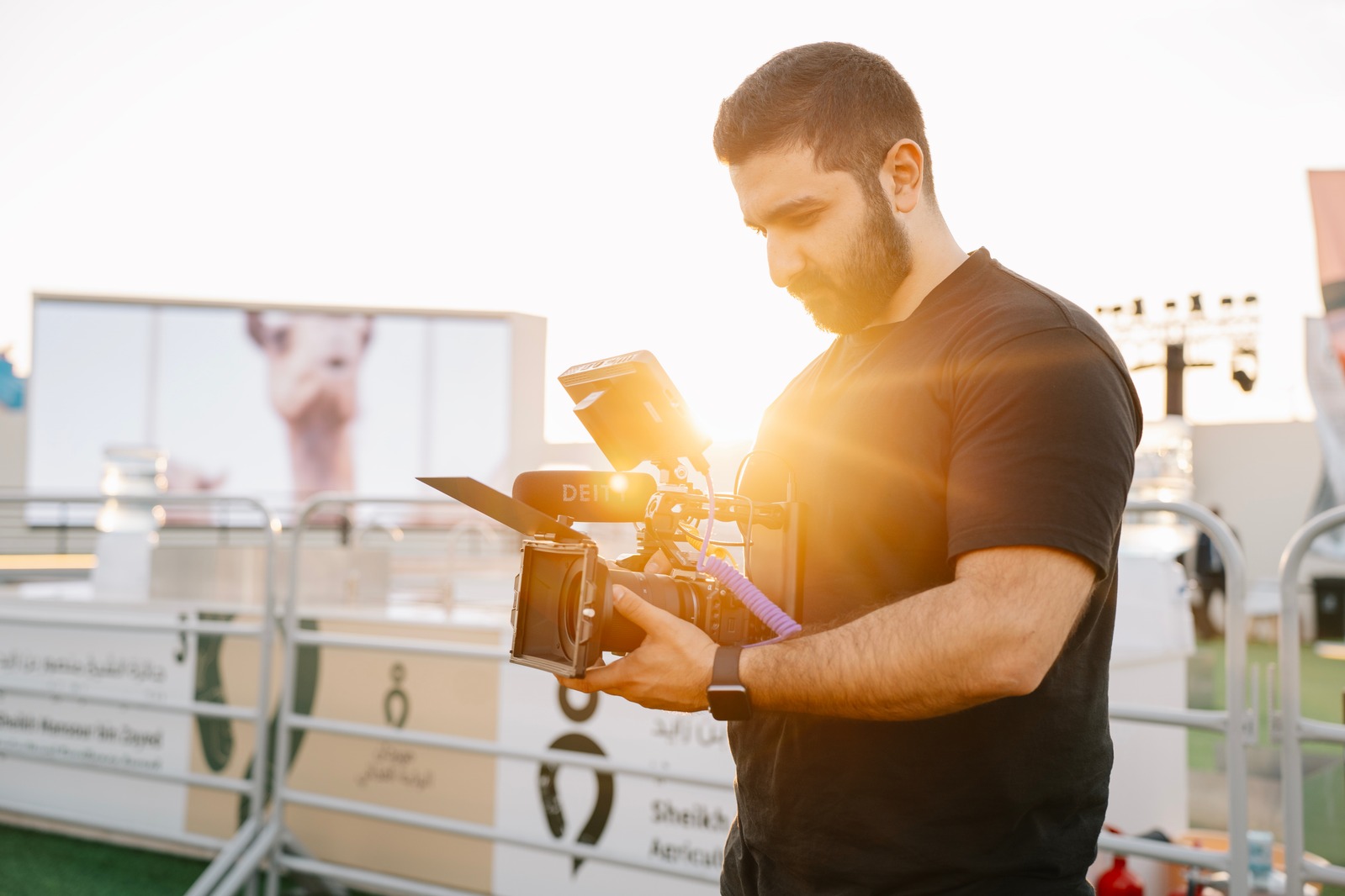 Moris Dakar holding a camera in front of a large screen