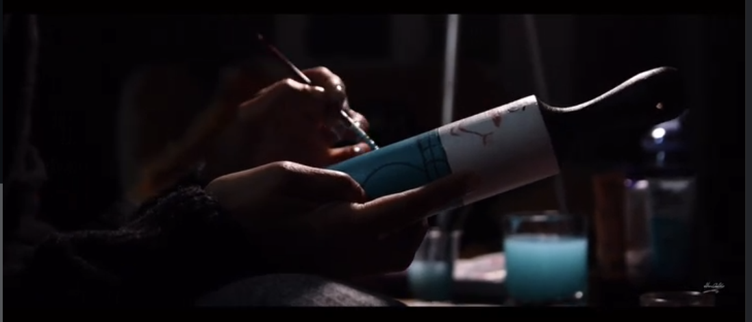 An artist hand-painting a bottle for the Le Ciel campaign.